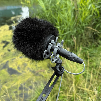 Black furry microphone windscreen attached to handheld camera mic on stand