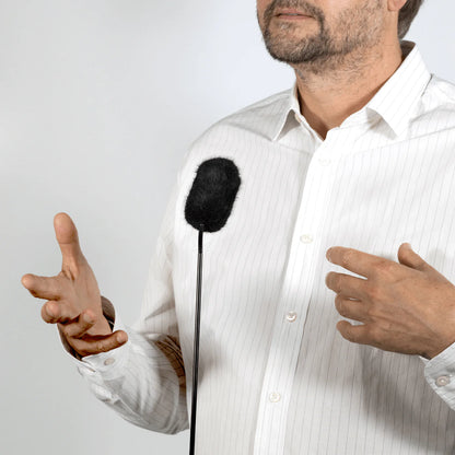 Black furry windscreen on a microphone held near a man for DPA